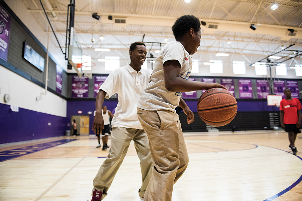 two male high-school aged students playing one on one basketball