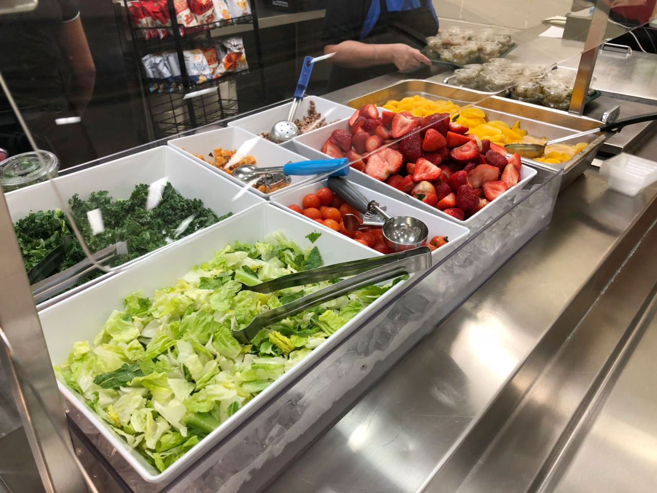 Salad bar with strawberries, peaches, lettuce, and kale