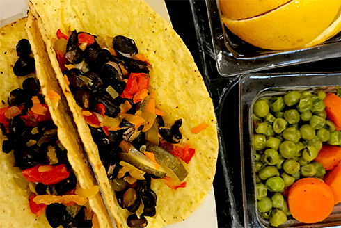 Black bean and veggie tacos with a side of peas and carrots with sliced orange