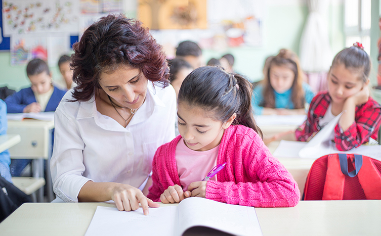 Teacher and elementary school student reading together.