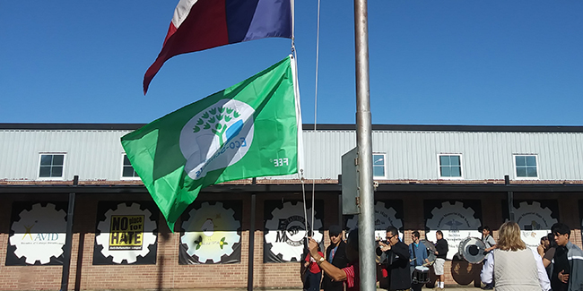 students raising eco green flag ceremony