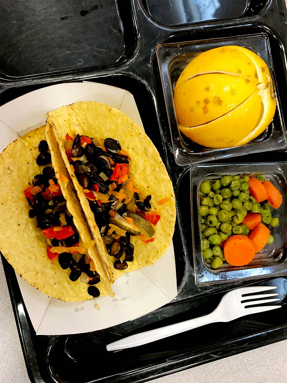 Black bean and veggie tacos with a side of peas and carrots with sliced orange