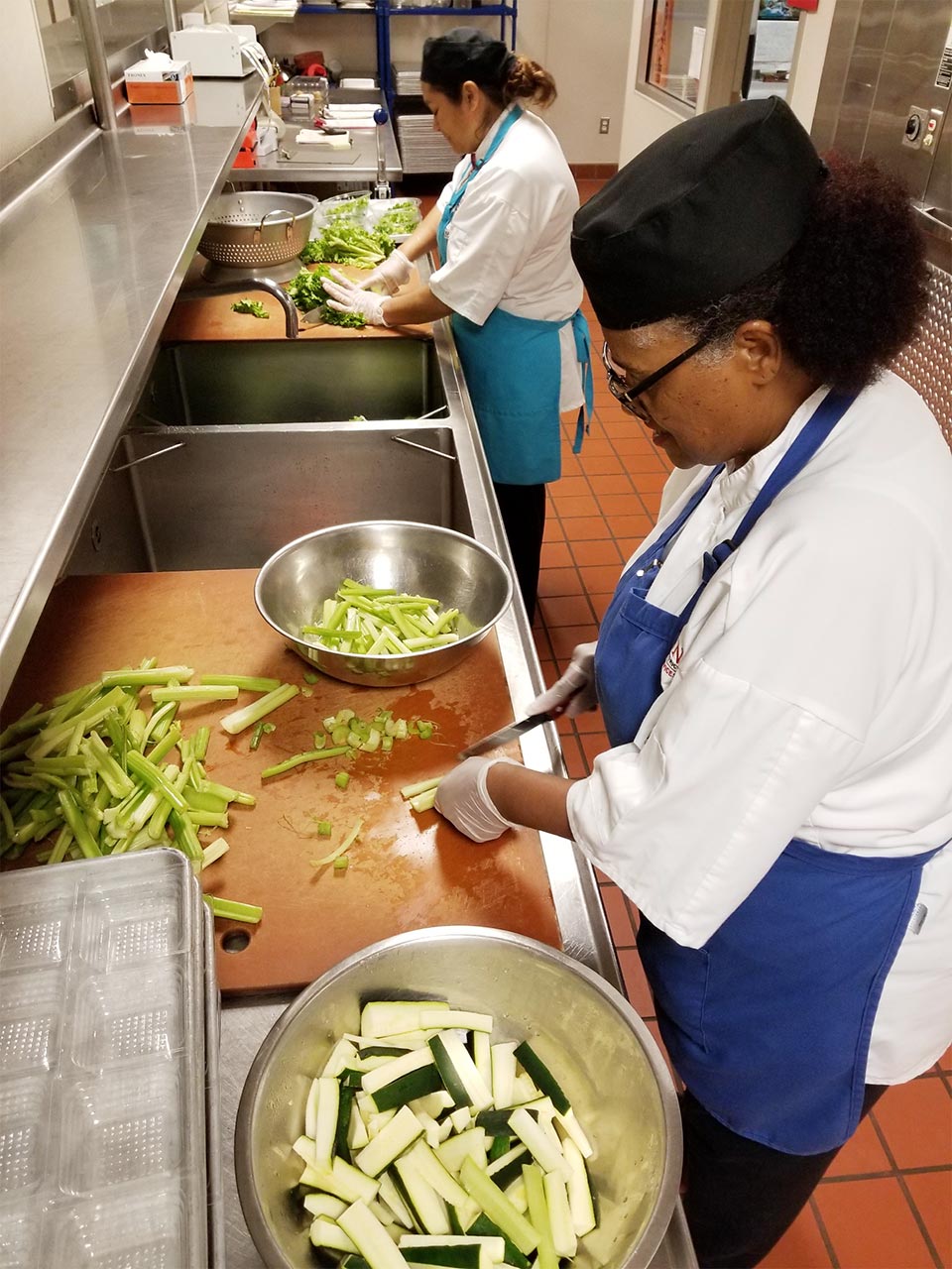 Two Food Services cooks dicing fresh zuchini