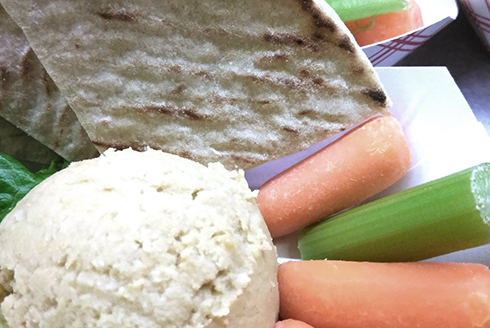 Vegan hummus plate with carrots, celery, and pita bread