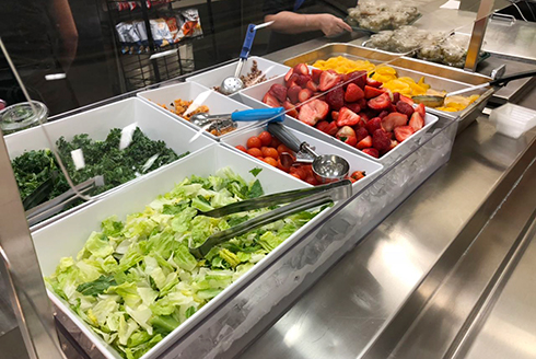 Salad bar with strawberries, peaches, lettuce, and kale 