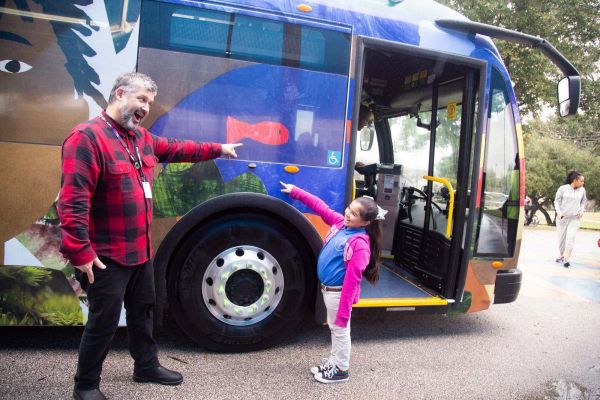 Student and her art teacher pose and point to where her artwork is on the bus