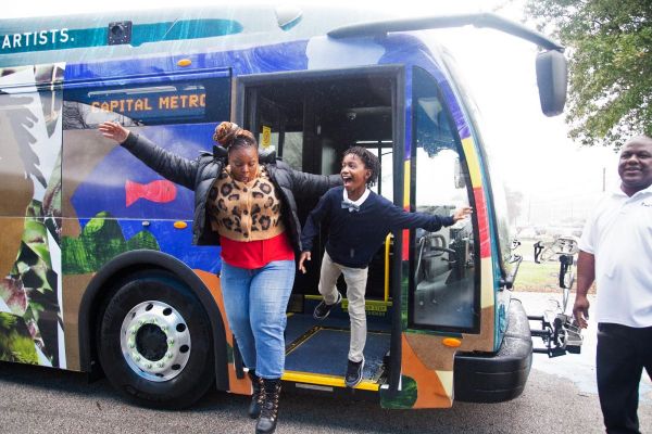 Student and his mother jump playfully from the bus front step
